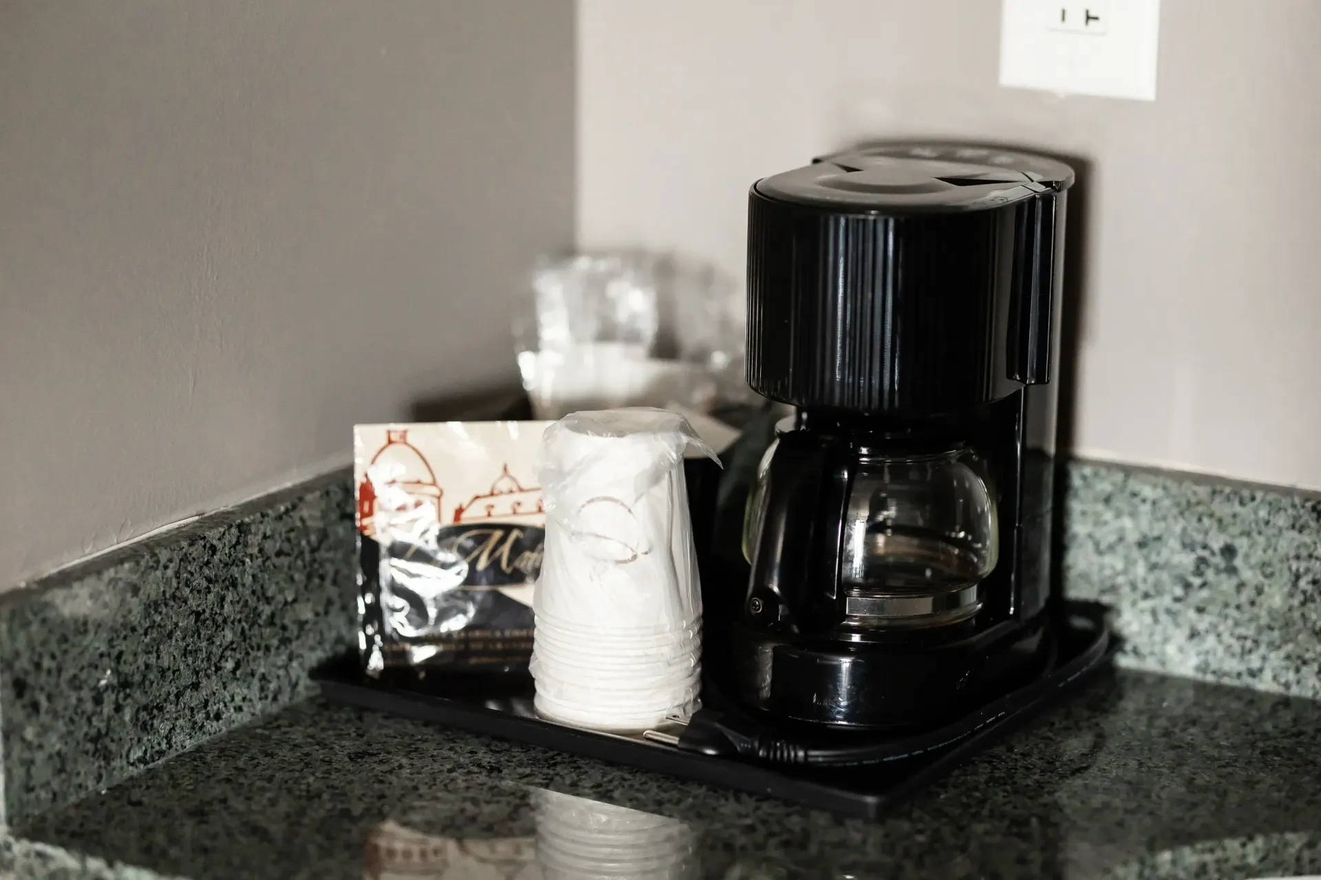A coffee maker is sitting on a counter next to a cup of coffee.