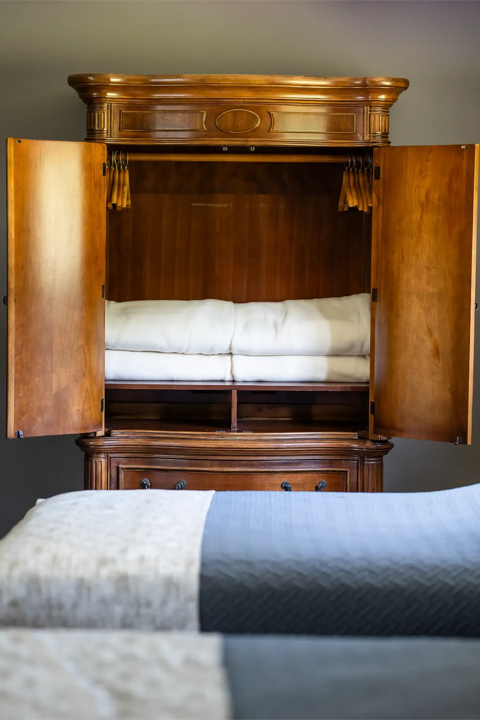 A bedroom with two beds and a dresser with the doors open