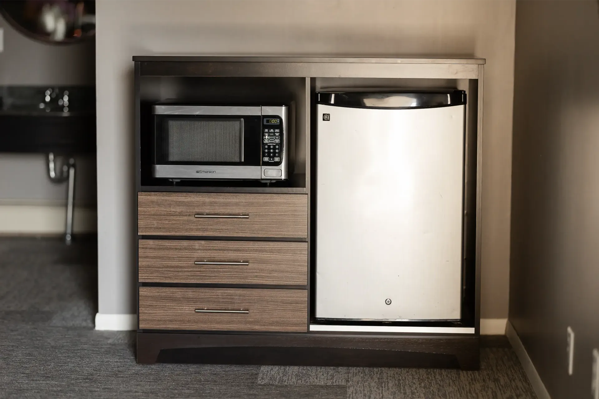 A hotel room with a microwave and a refrigerator