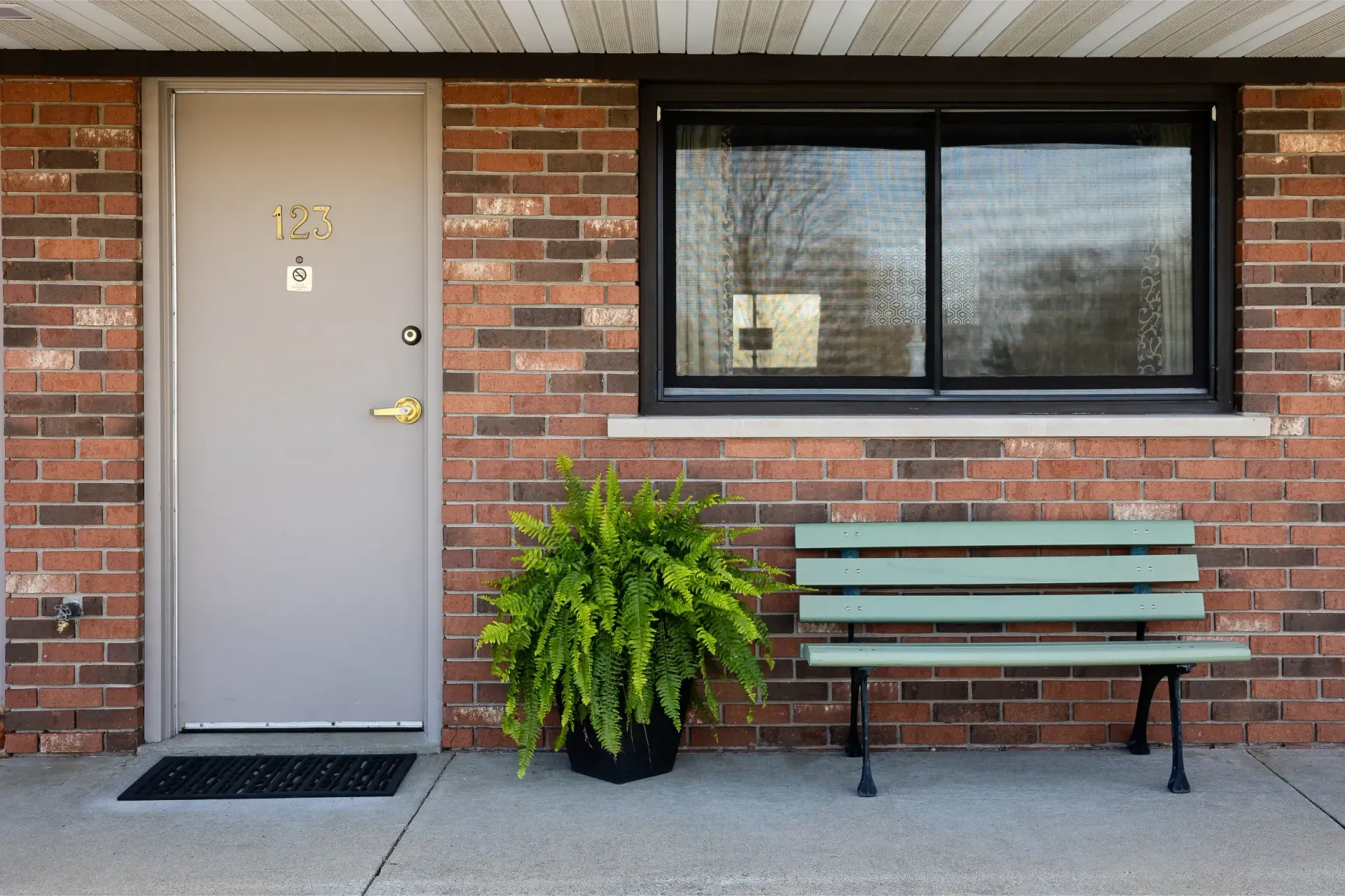 A green bench is sitting in front of a brick building.