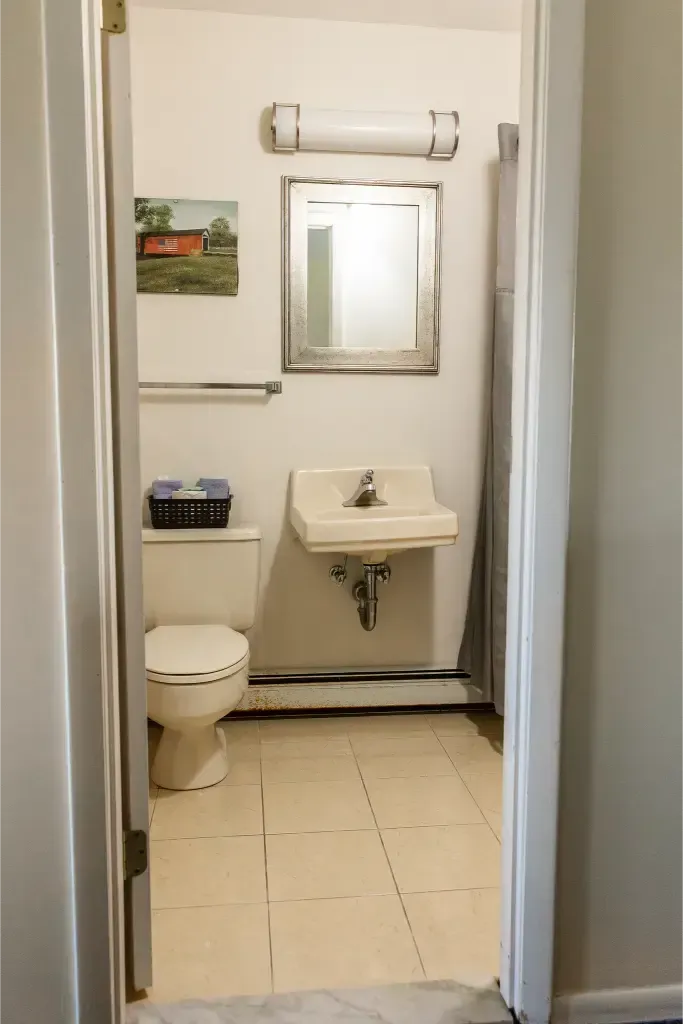 A bathroom with a toilet , sink and mirror