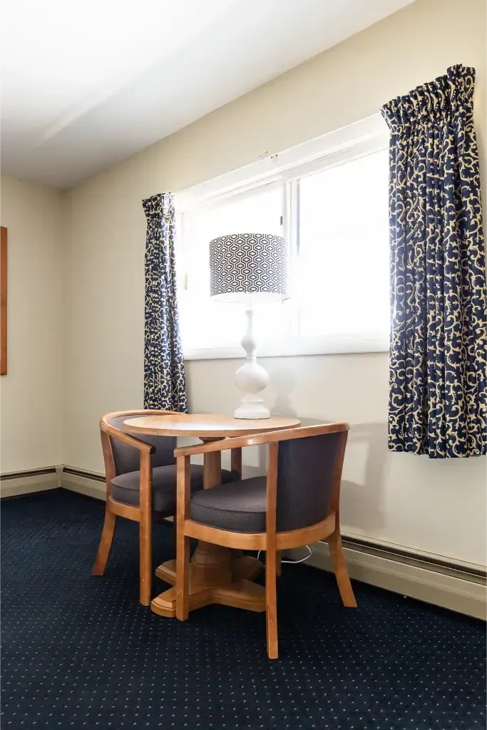 A room with two chairs and a table with a lamp on it