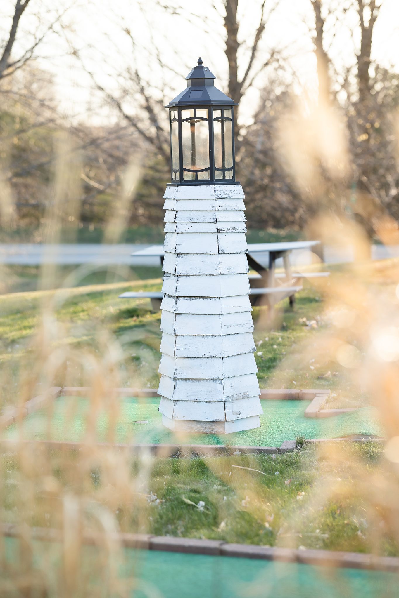 A white lighthouse is sitting in the middle of a golf course.