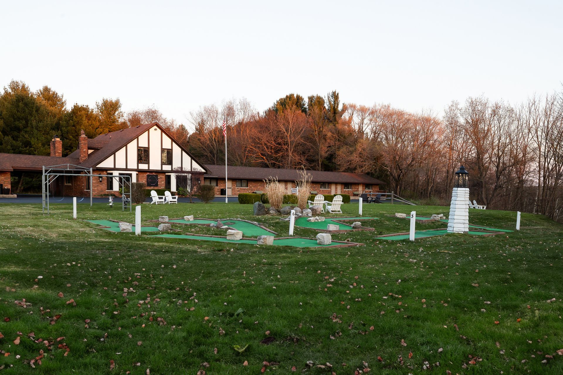 A small golf course with a lighthouse in the middle of it in front of a house.