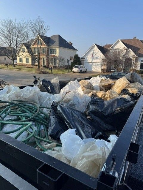 Trash Talkers crew member loading household junk into a dump trailer at a Kankakee County home