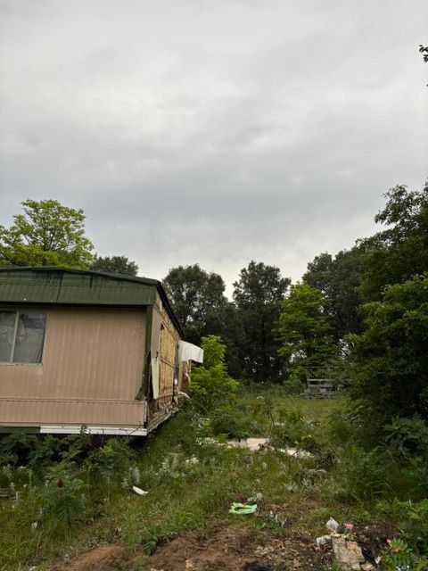 Worker demolishing wood-frame outbuilding wall with sledgehammer in Kankakee County, Illinois