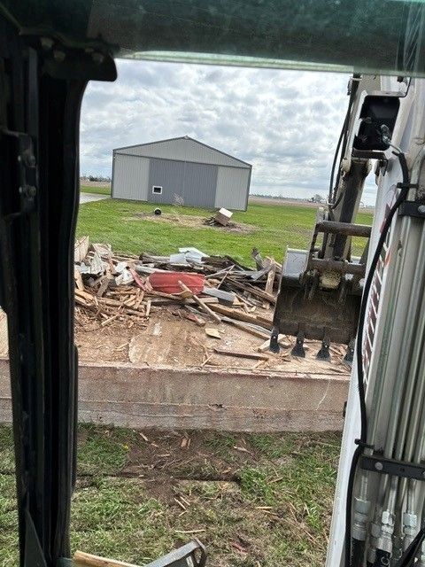 Tradesperson operating mini excavator at a residential demolition site in Kankakee County, Illinois