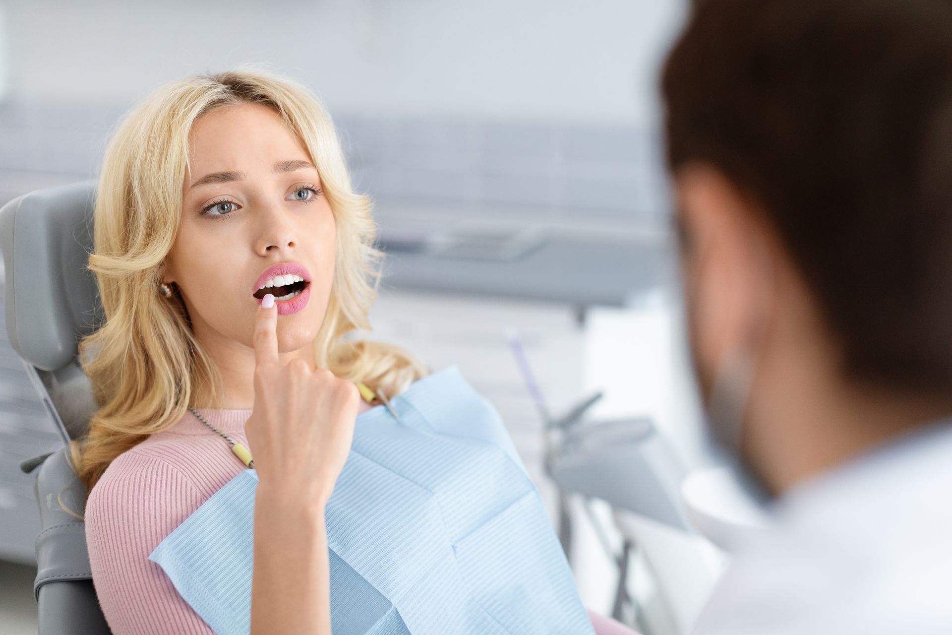 Patient opening mouth for dental exam while dentist examines her in a bright clinic