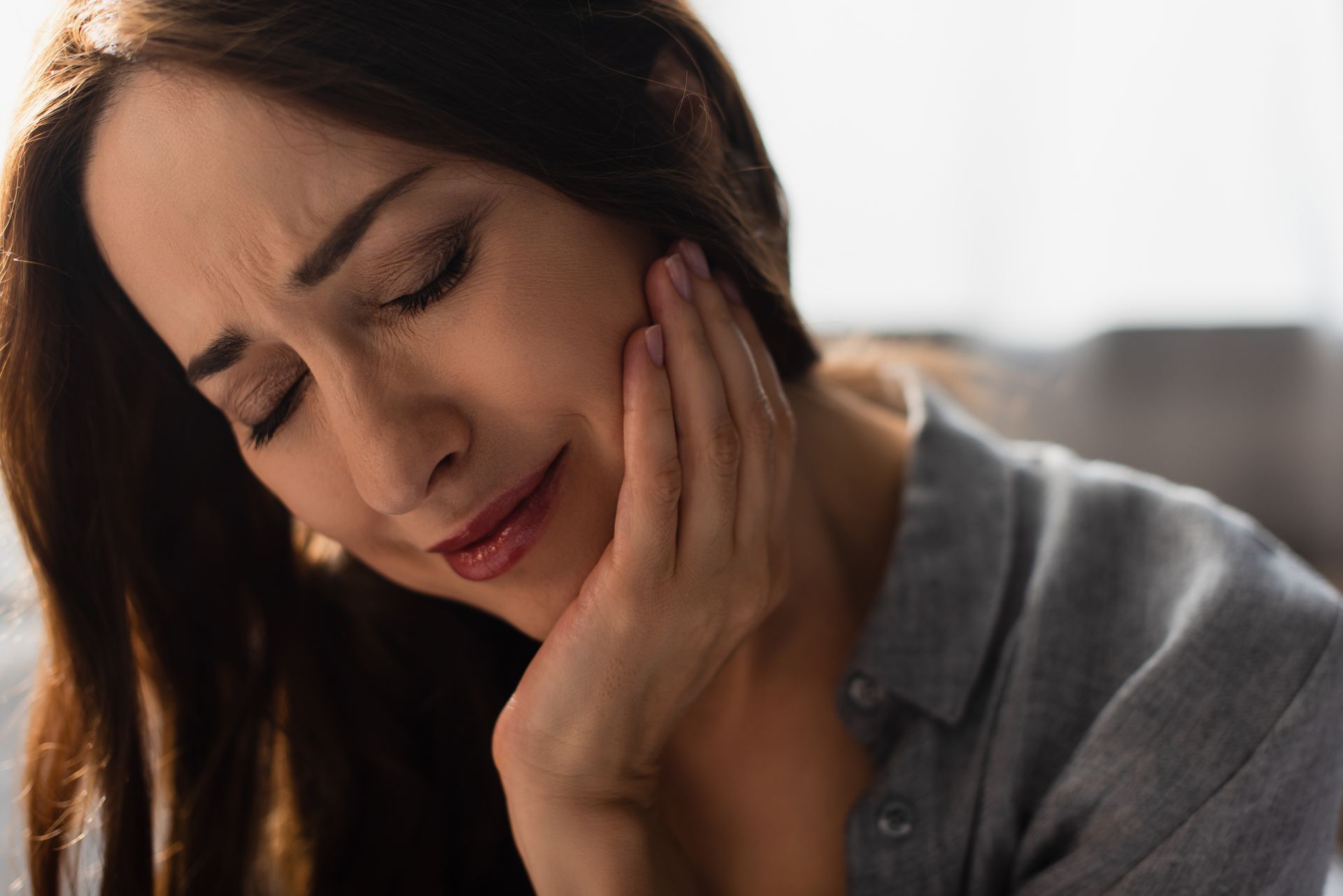 A woman is holding her face in pain because of a toothache.