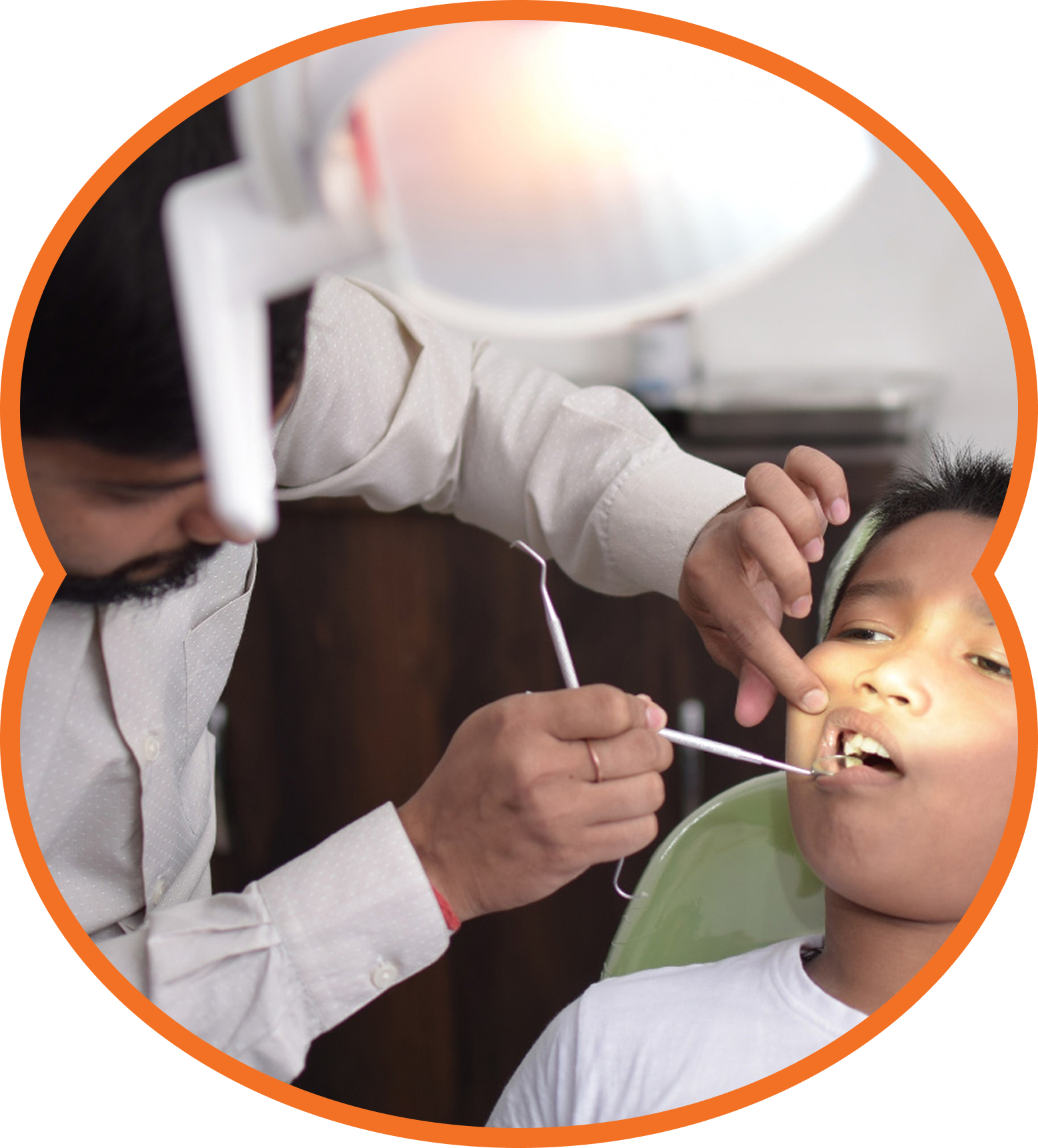 Dentist examining a child’s mouth with a dental mirror under a bright exam light