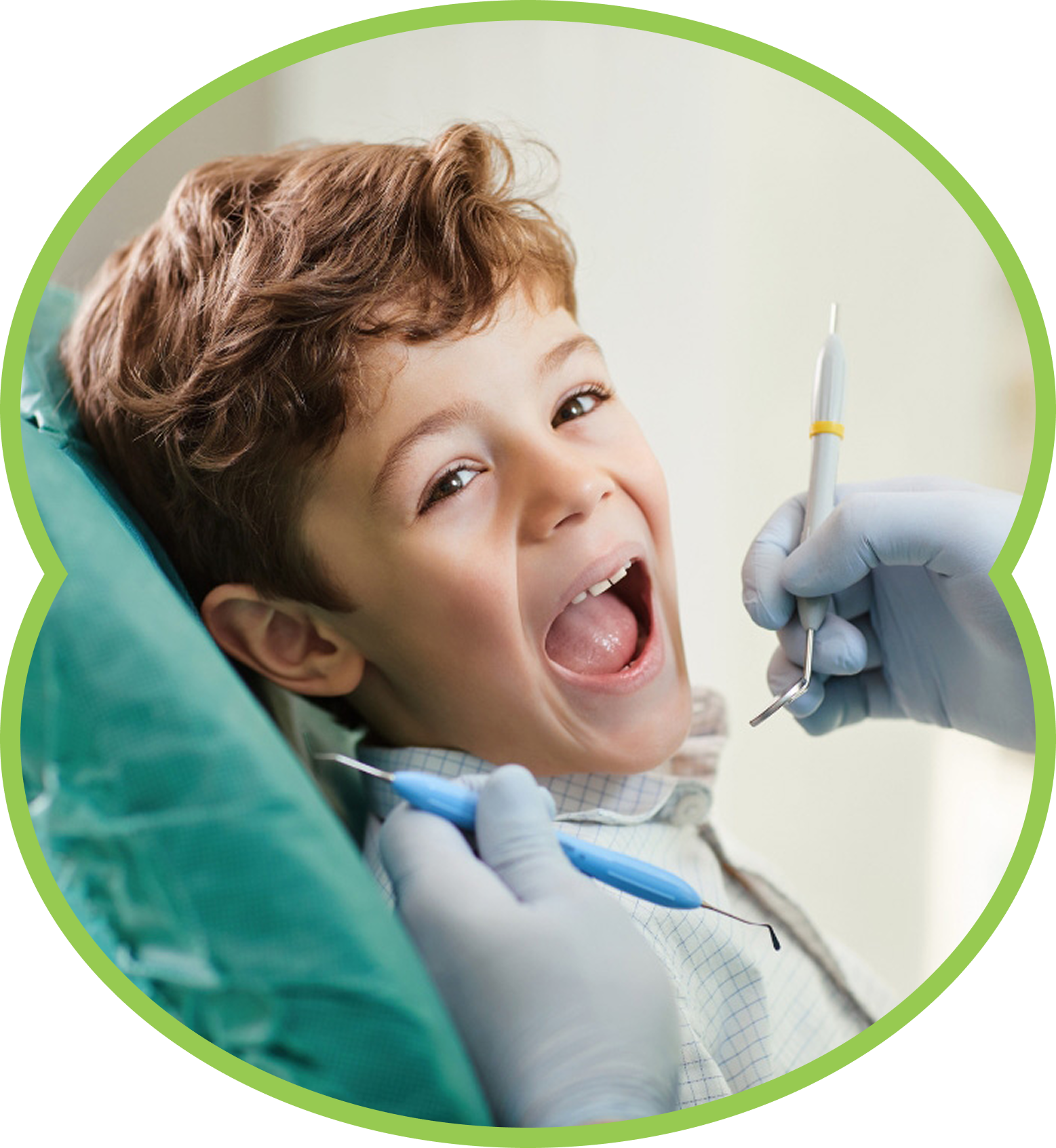 Child in a dental chair smiling as a dentist uses tools during an exam