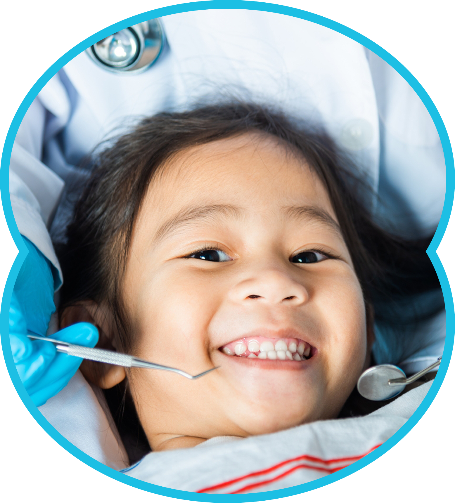 Smiling child in a dental chair with a dentist’s tools near the mouth