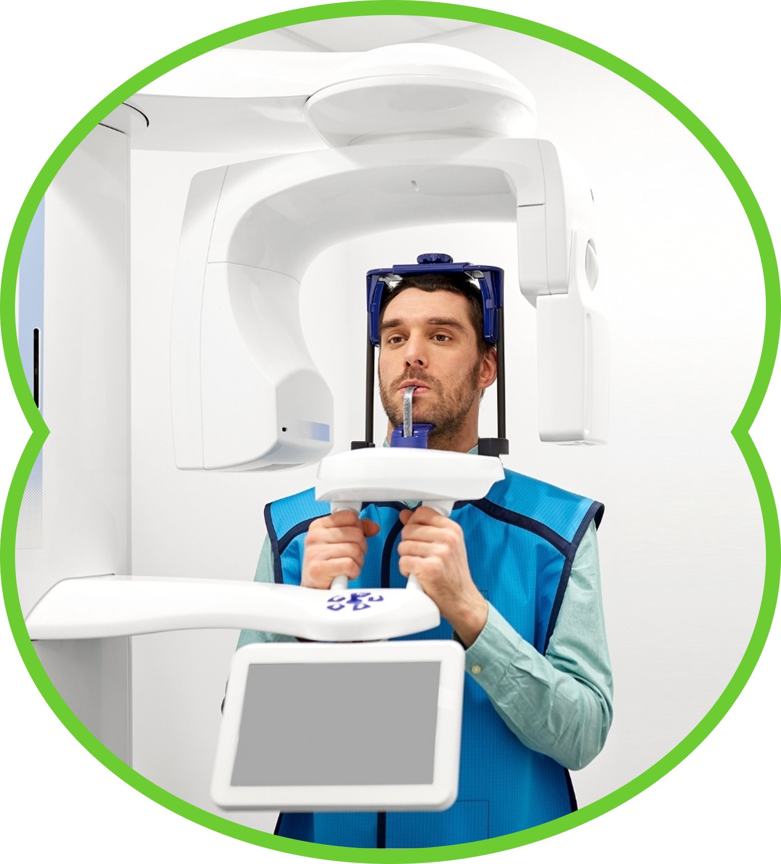 Dentist using dental X-ray machine in a bright clinic, with patient head frame and monitor in view