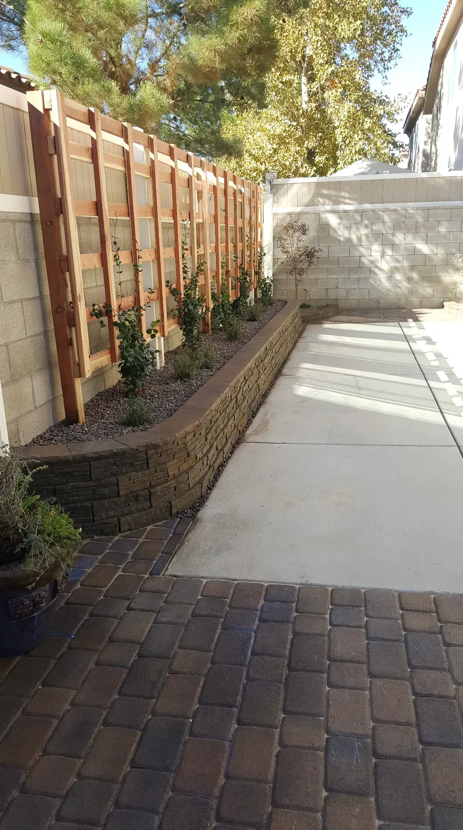Backyard with retaining wall, walkway, wooden fence, and landscaping.