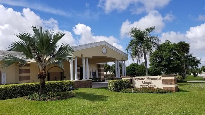 Eternity Memorial Chapel, beige building with columns, green lawn, palm trees, blue sky.