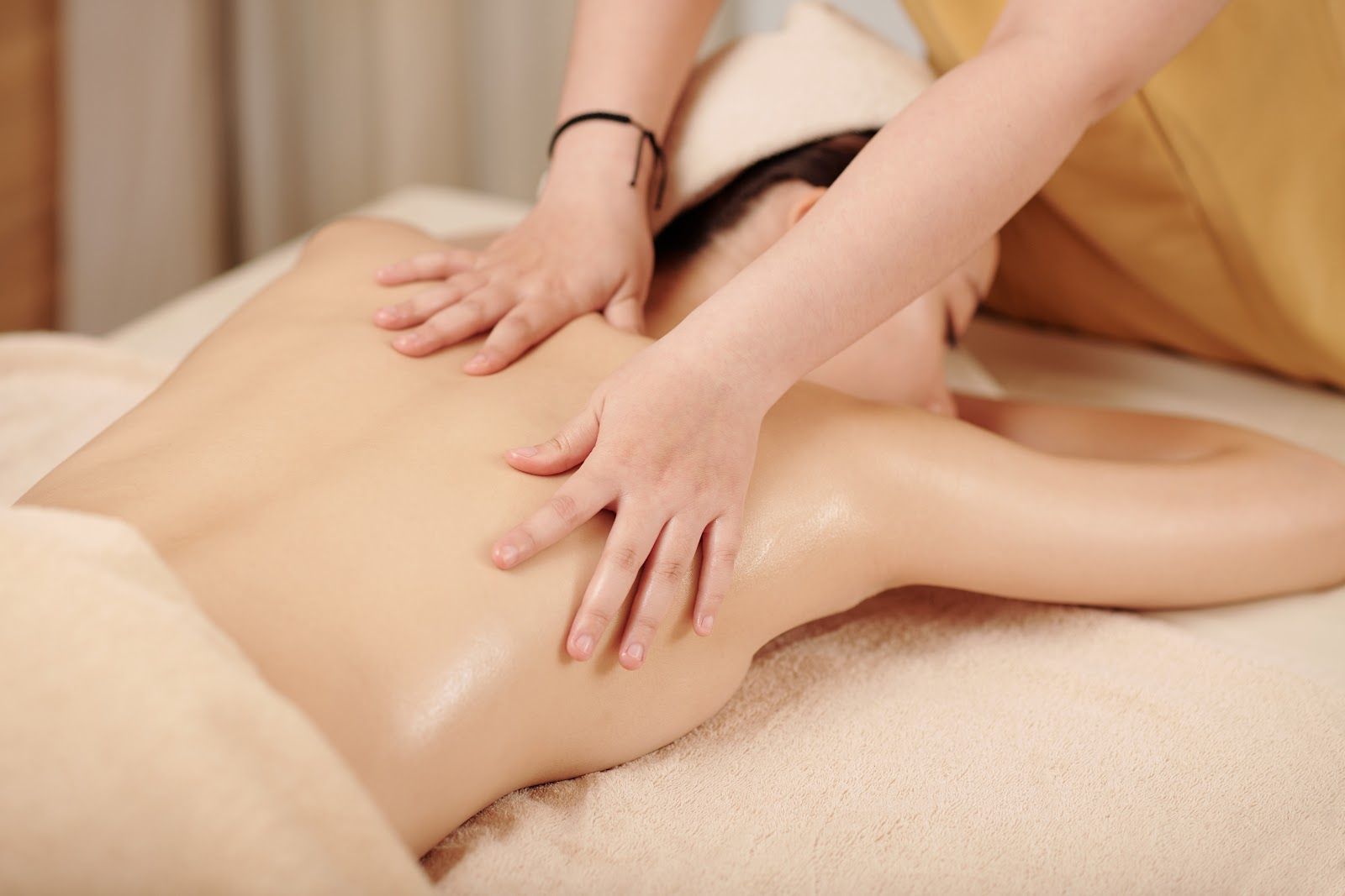 Massage therapist working on a client’s bare back on a treatment table