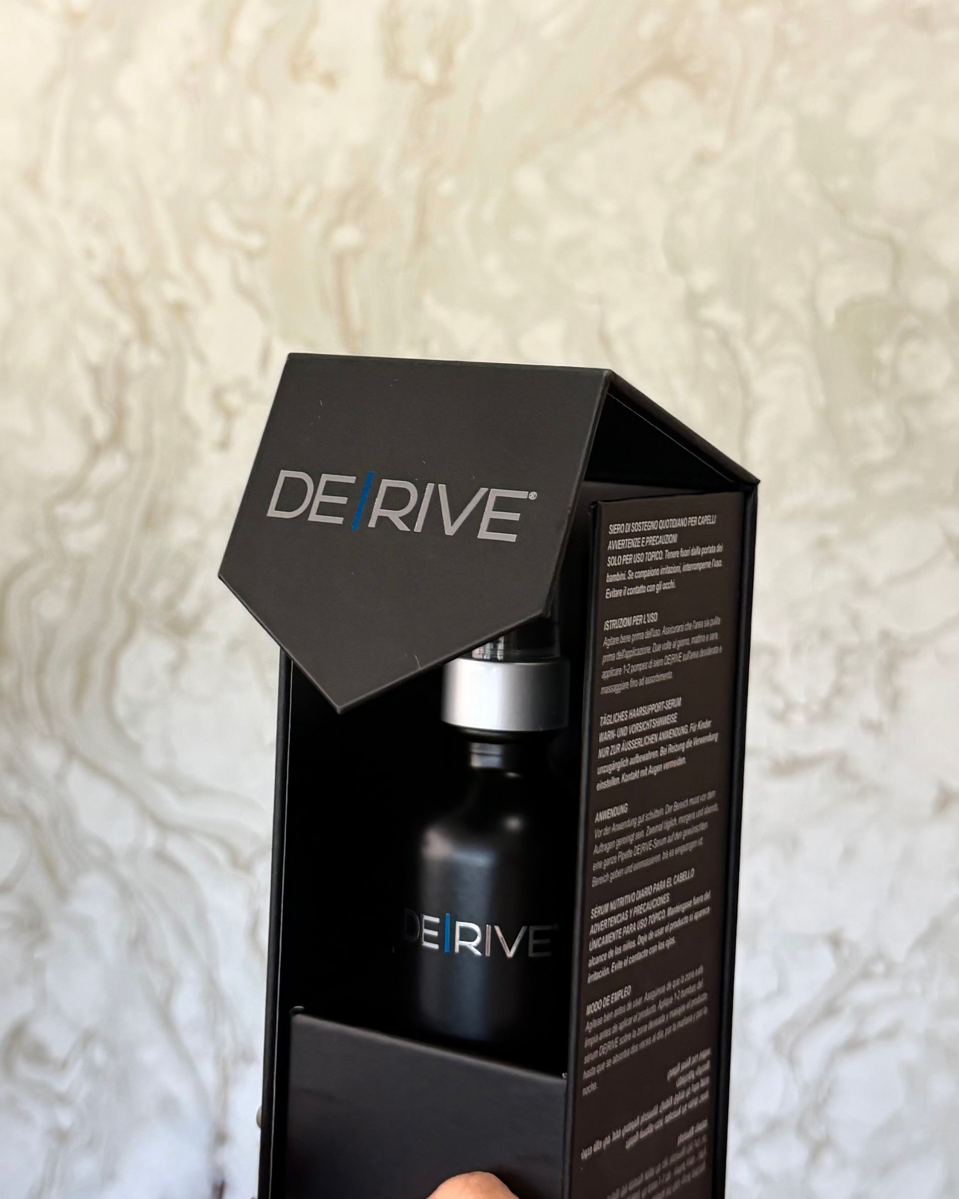 Black DERIVE product box with a silver-capped bottle on a shelf against a light wall