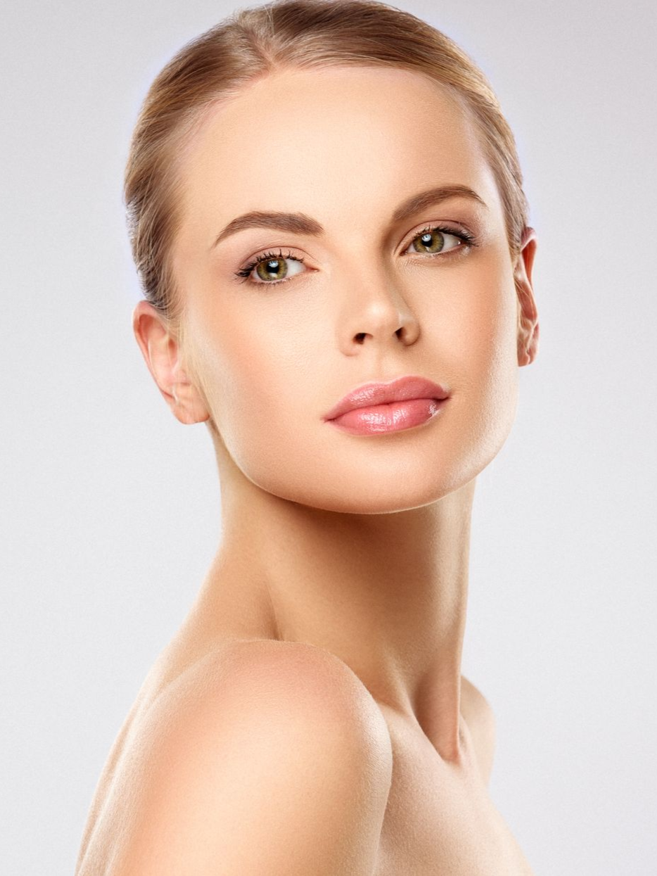 Portrait of a woman with smooth skin and tied-back hair against a light background