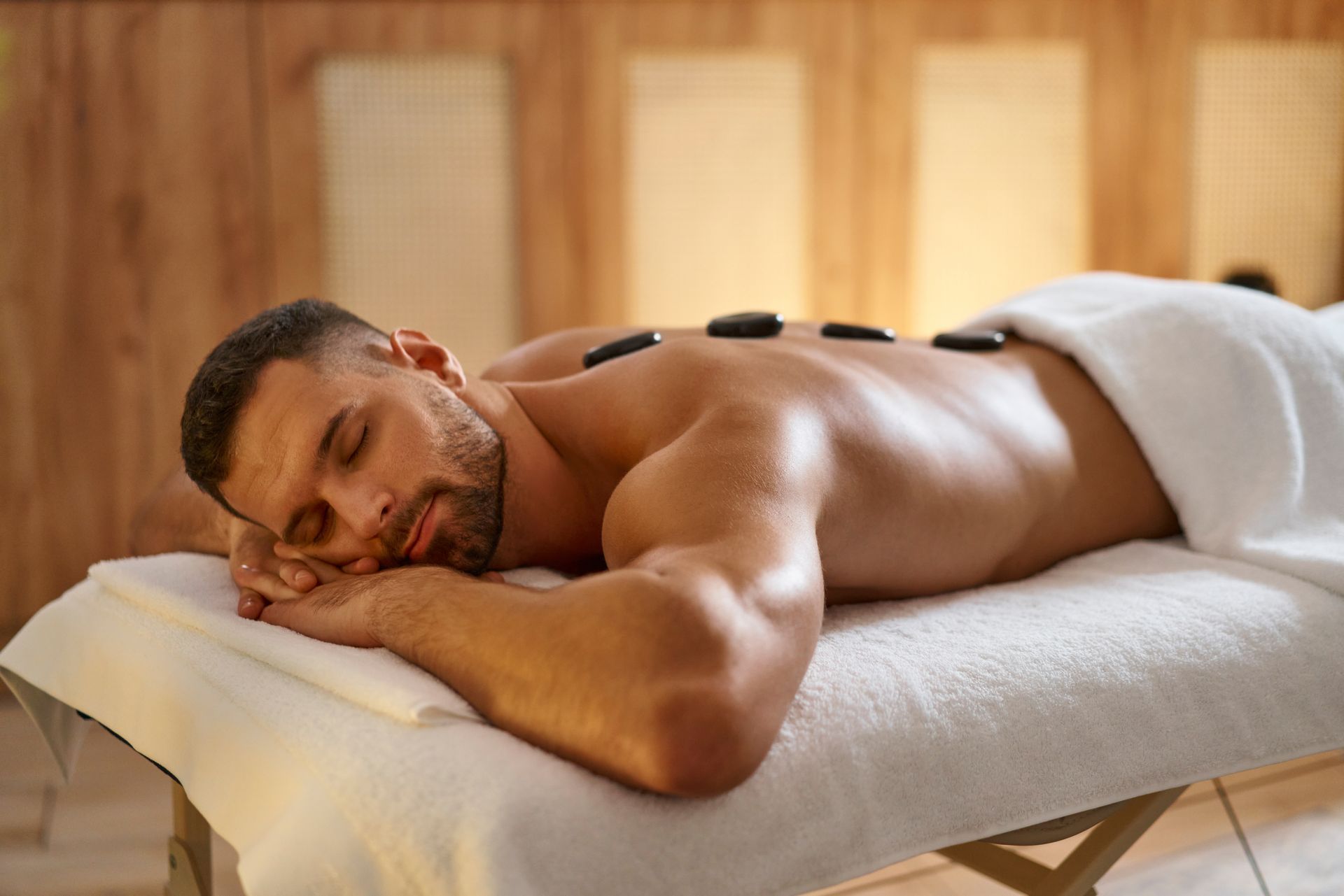 Man lying face down on a massage table with eyes closed in a spa room
