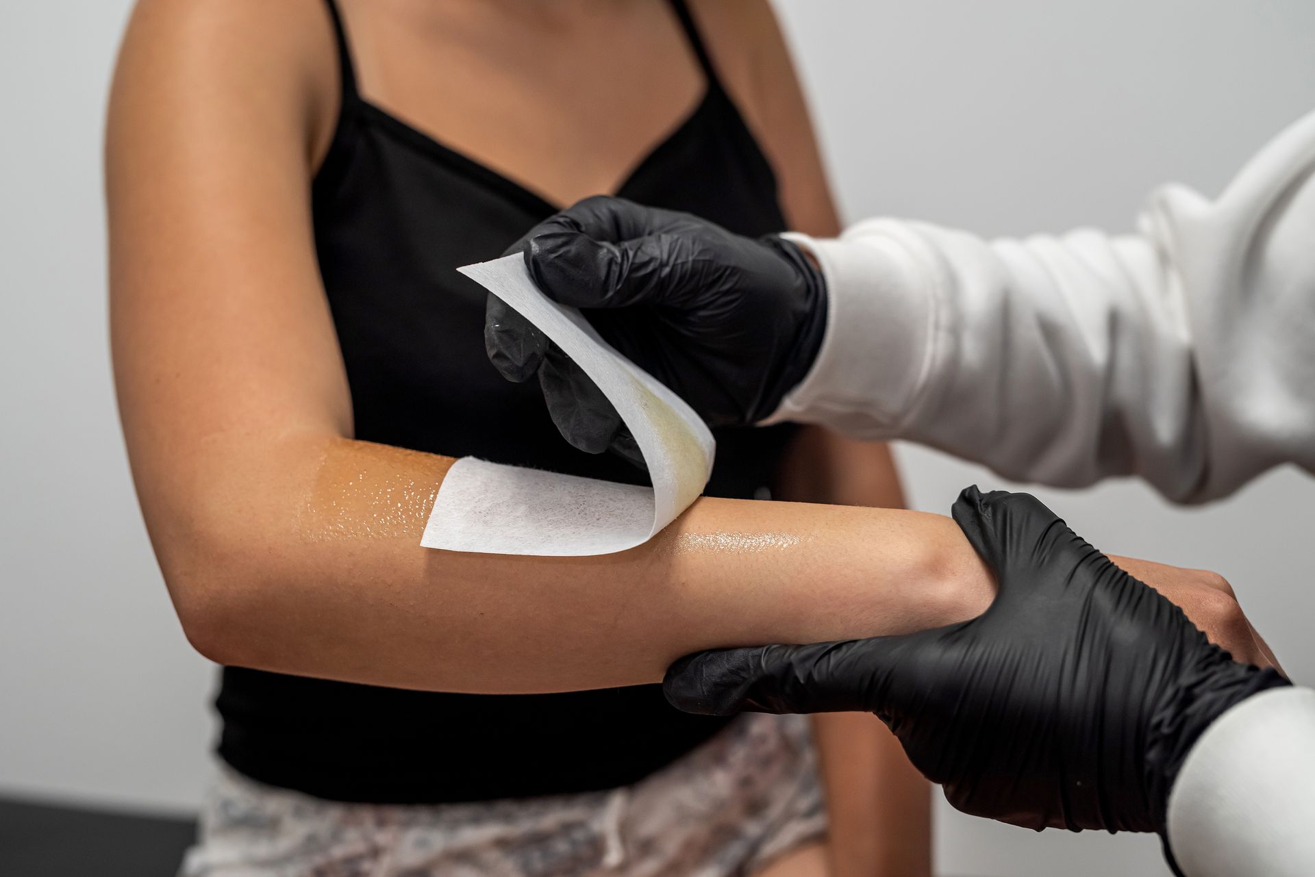 Gloved hands apply a white bandage to a person’s upper arm.