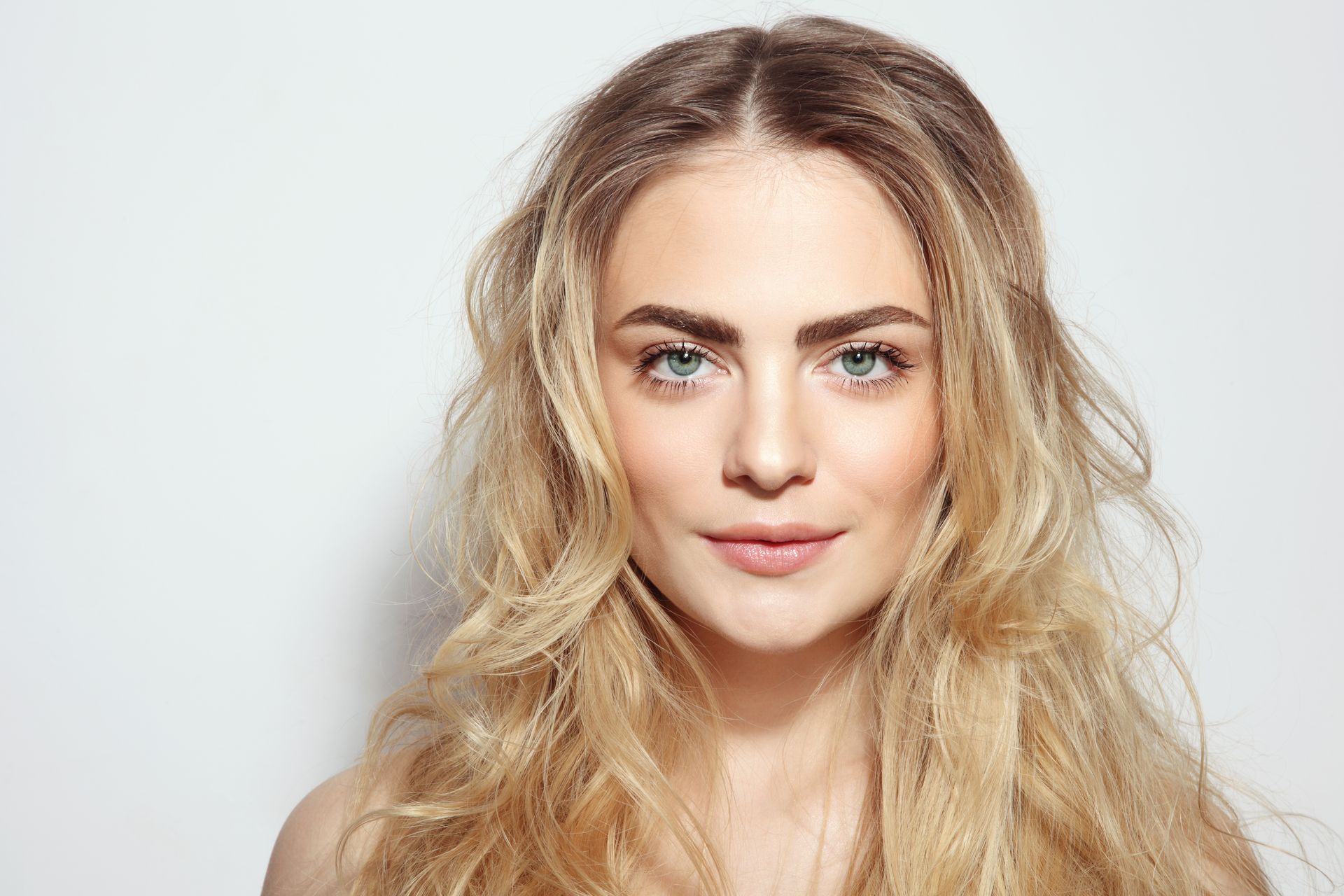 Portrait of a woman with long blonde hair against a light gray background