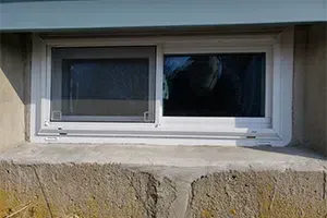 Tape measure stretched across a small basement window as a person measures the width.