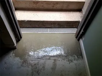 Open white basement stairwell with red metal hatch doors