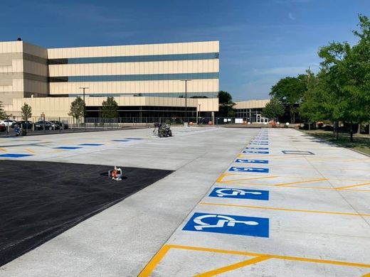 Empty parking lot with blue accessible spaces beside a beige office building under a clear sky