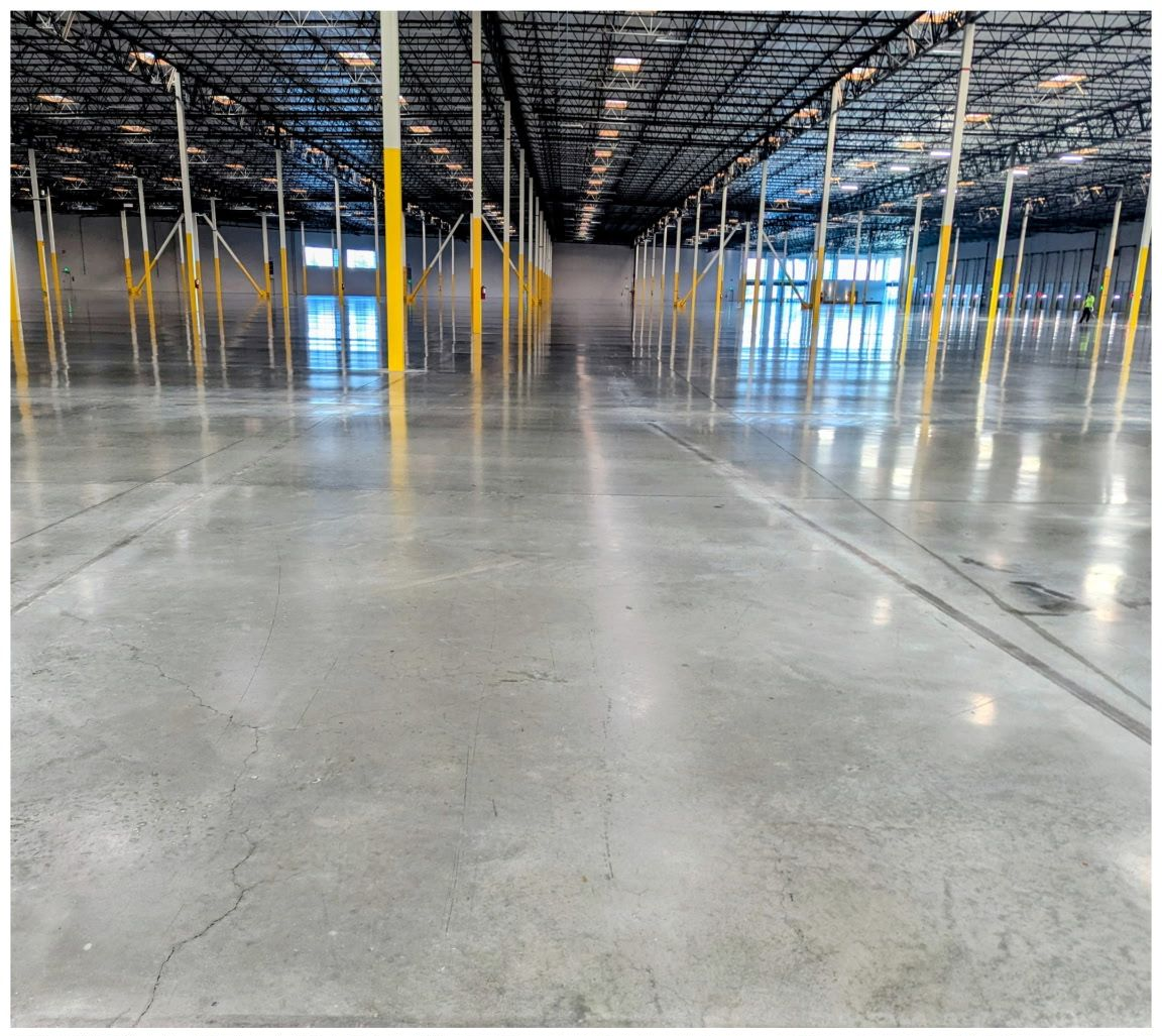 Empty warehouse interior with polished concrete floor, exposed ceiling, and yellow support columns