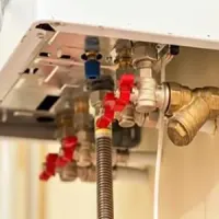 Close-up of gas appliance plumbing with red shutoff valves and flexible metal hose underneath a unit