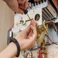 Hands adjusting a boiler control panel with a screwdriver and cable near copper pipes