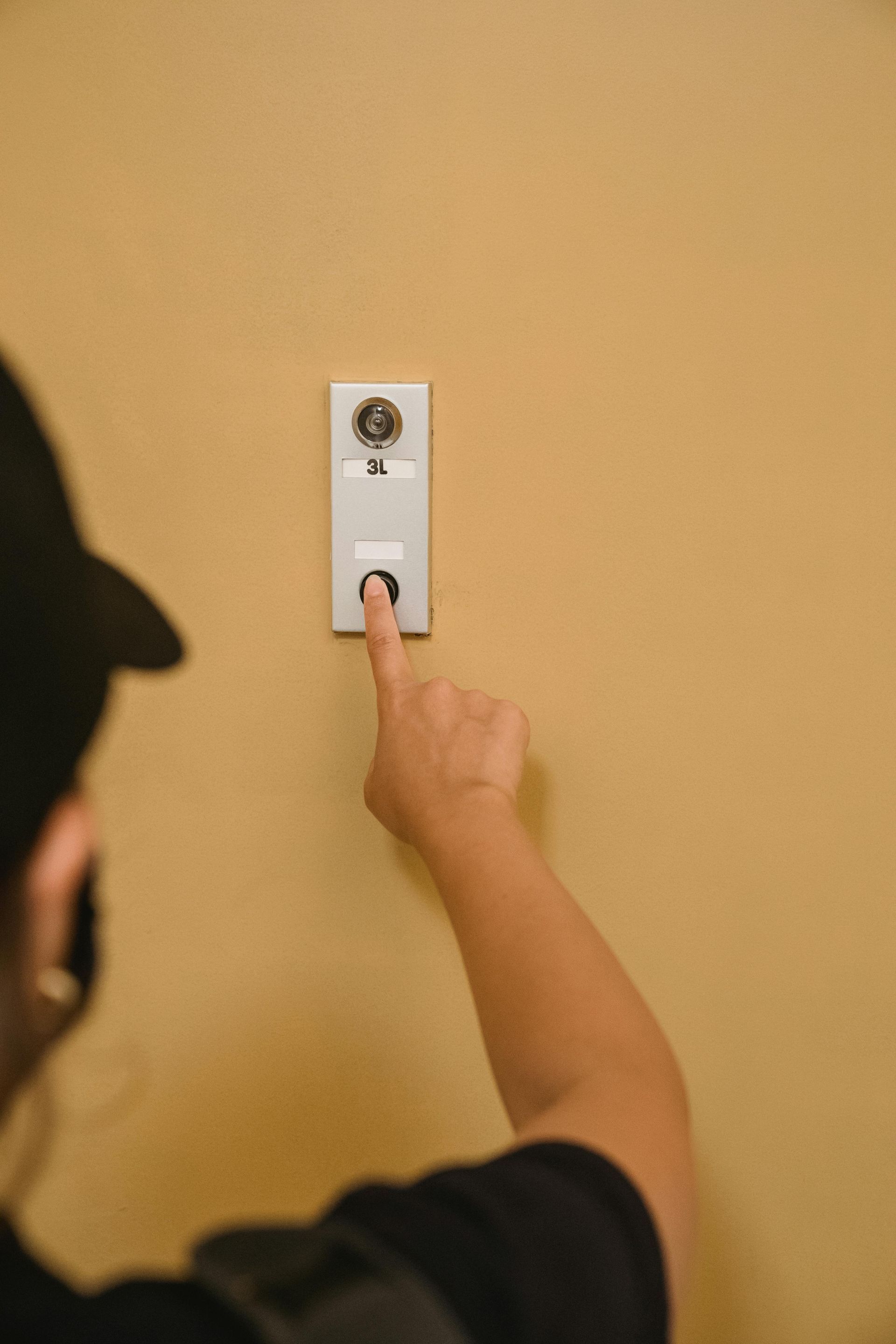 Hand pressing a white wall switch on a tan wall