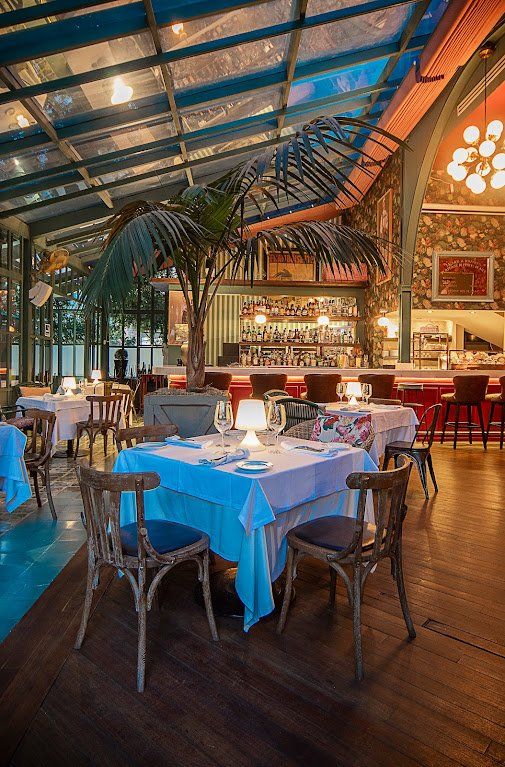 Elegante comedor de restaurante con manteles blancos, iluminación cálida y techo de cristal.