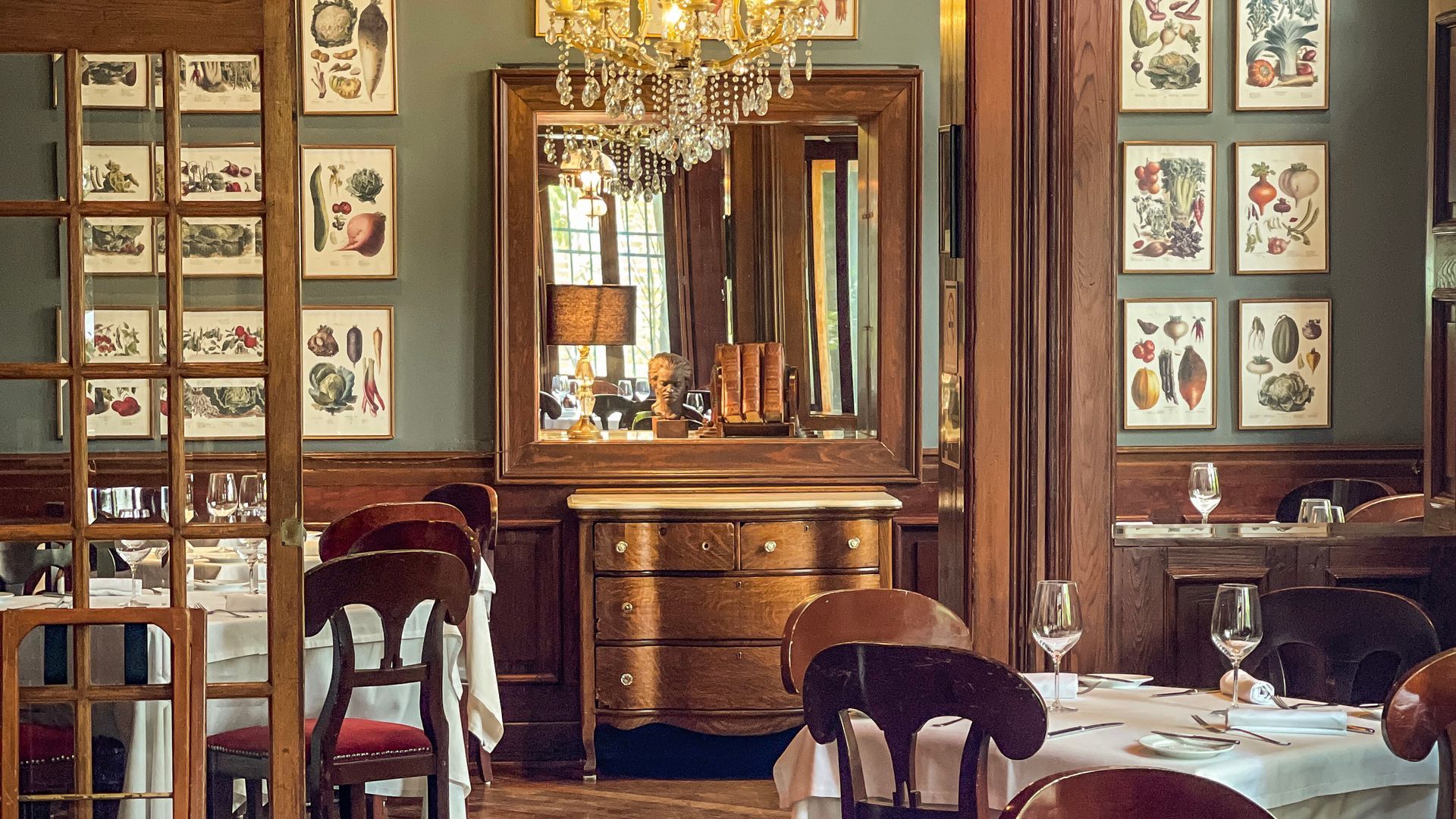 Elegante comedor con decoración vintage, lámpara de araña, cuadros y mesas