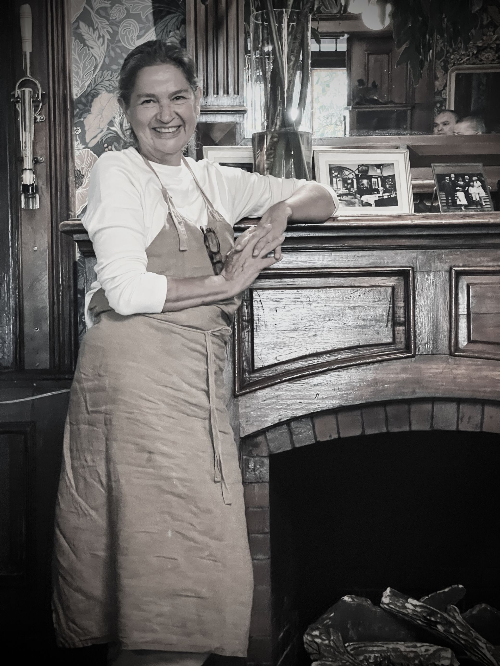 Mujer con delantal junto a chimenea antigua