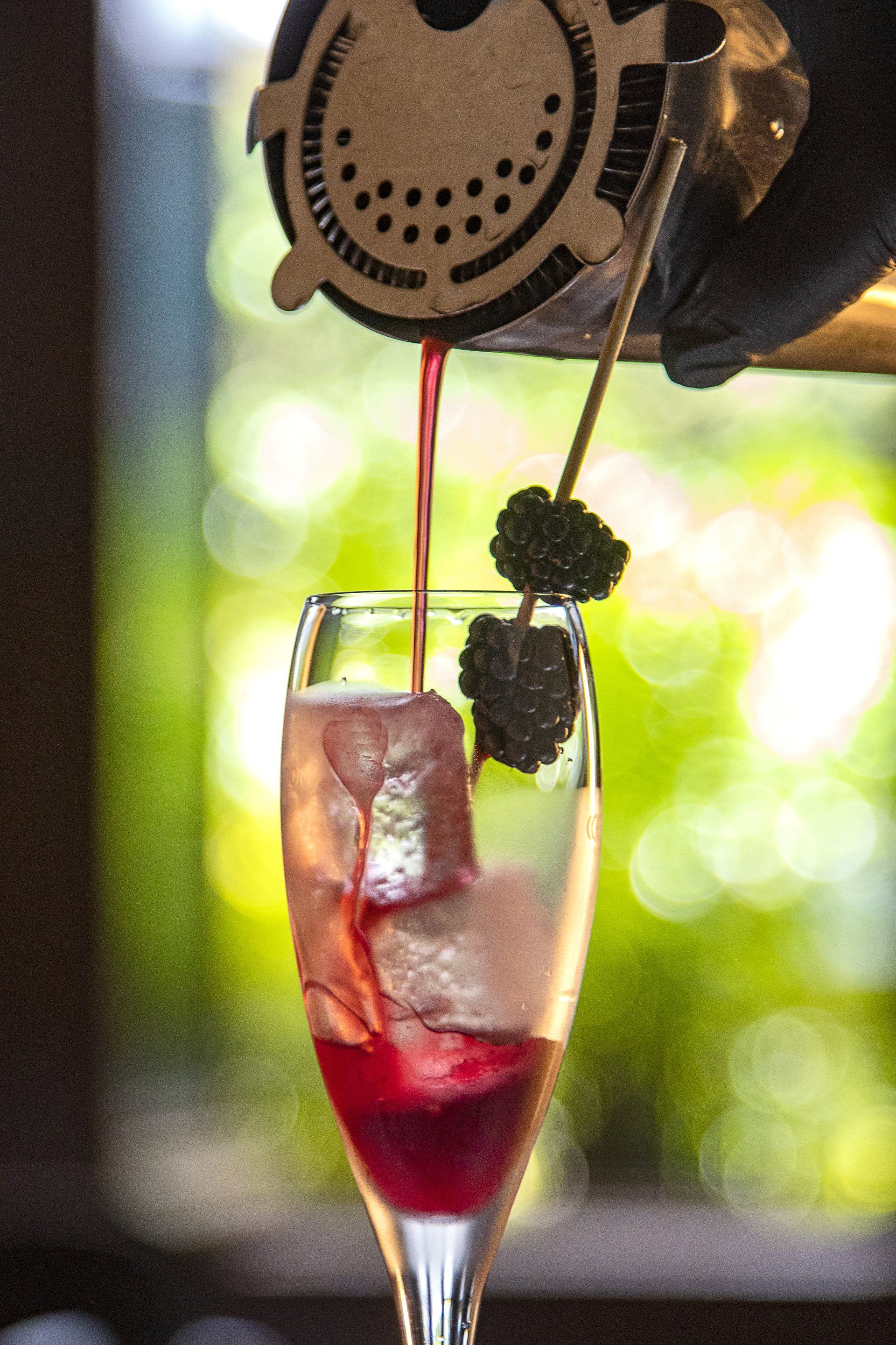 Se sirve vino en una copa alta con hielo y frutos rojos procedentes de un dispensador, al aire libre.