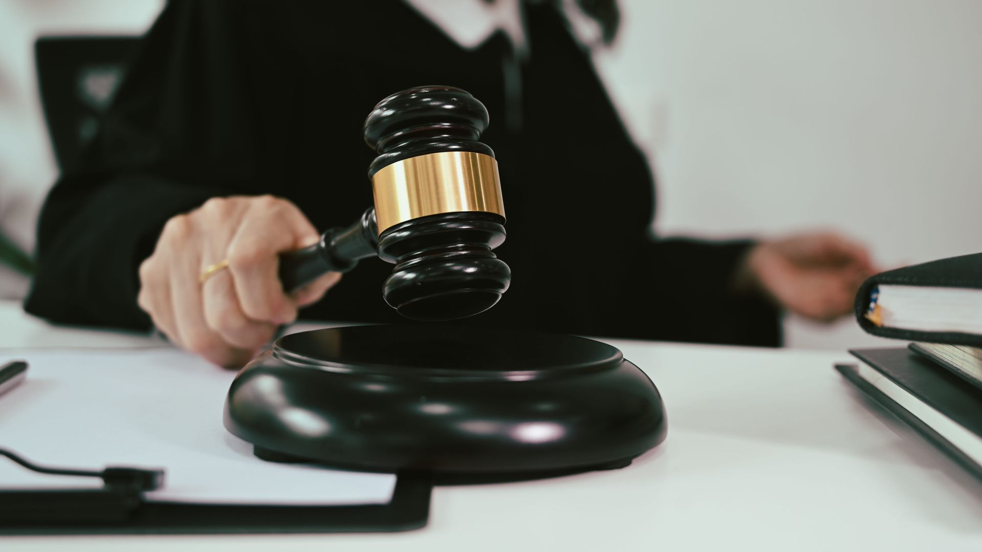 Judge’s gavel striking a black sound block on a desk in a courtroom setting