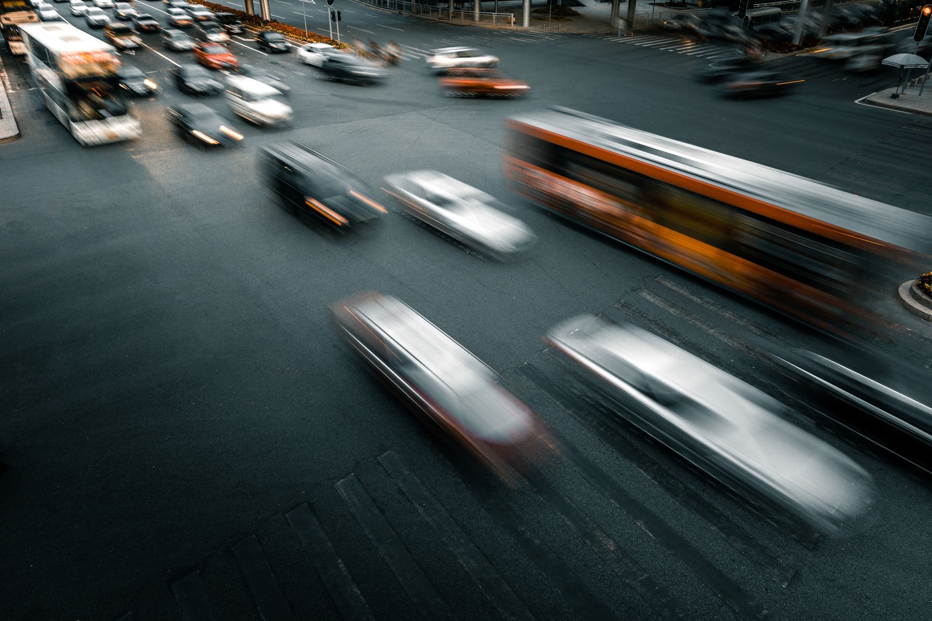 Cars and a bus blurred in motion on a city street at dusk.