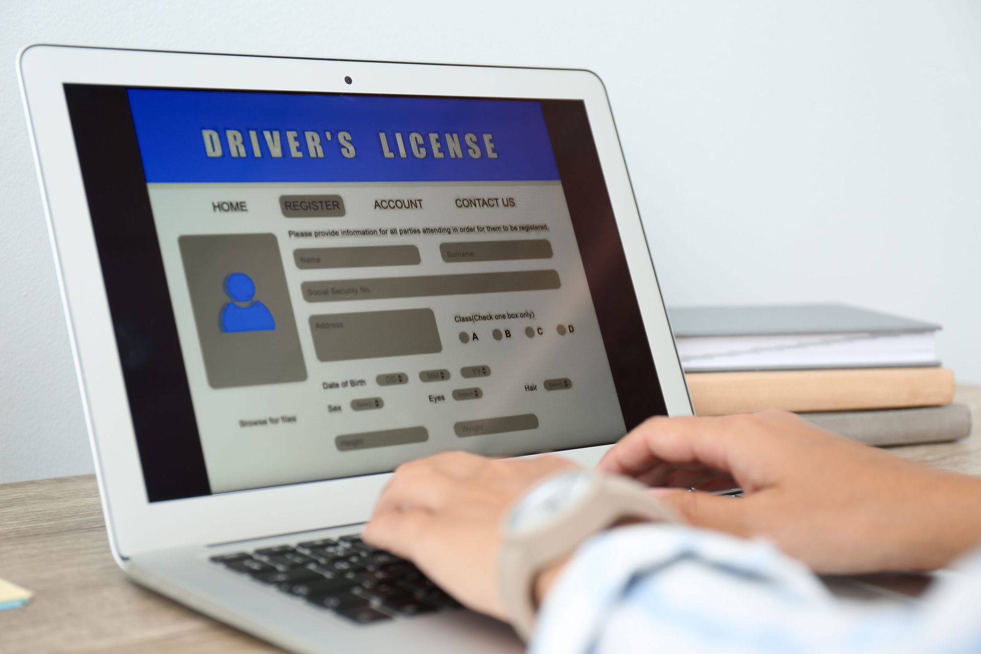 Hands typing on a laptop showing a driver’s license form
