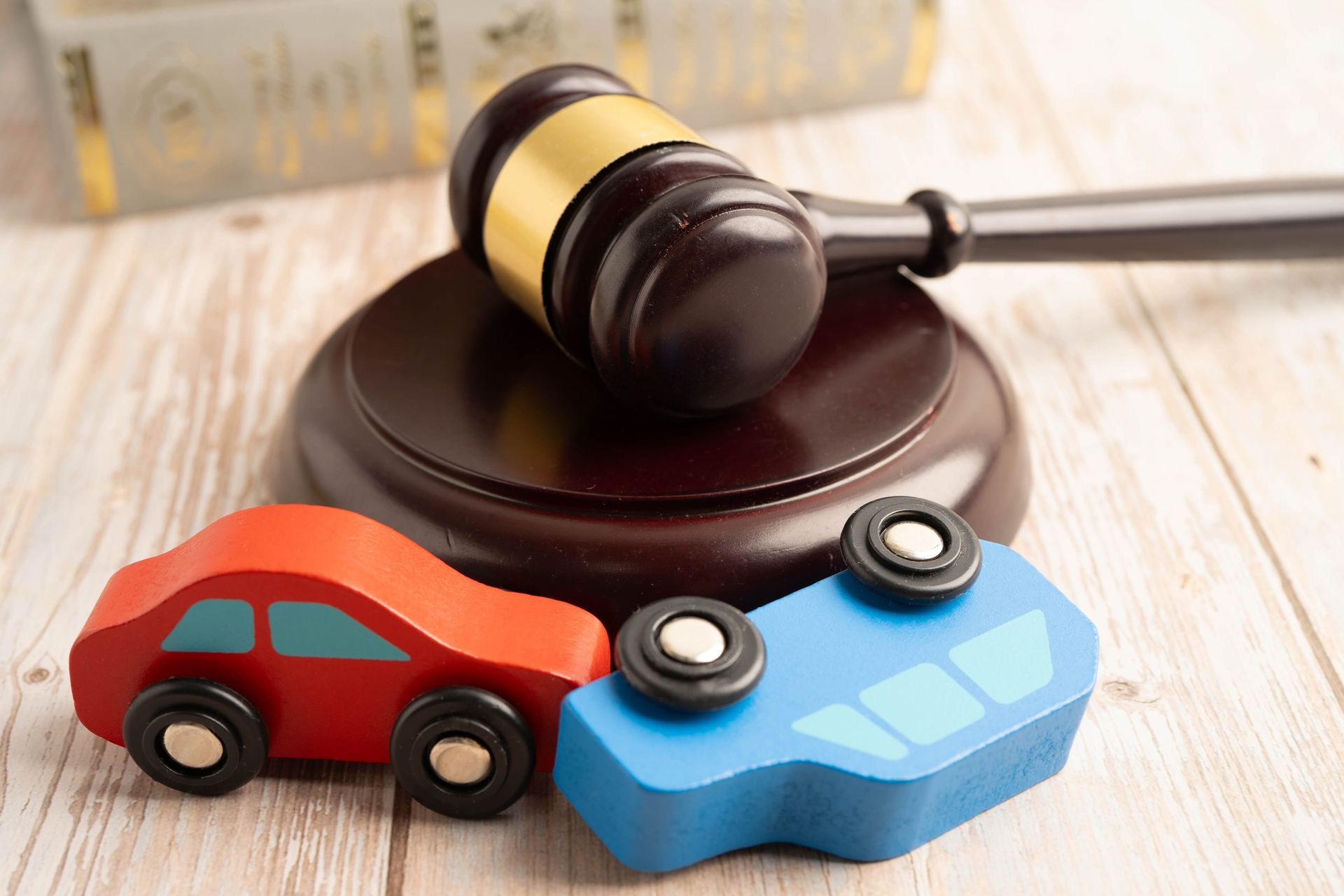 Toy cars and a gavel on a wooden surface, suggesting a car accident or legal dispute