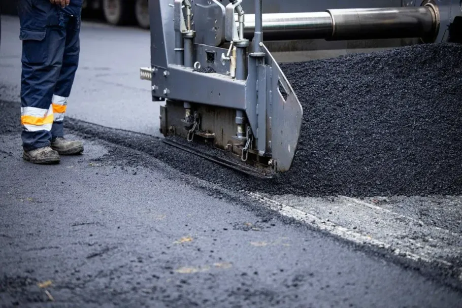 Asphalt paver machine laying new road surface.
