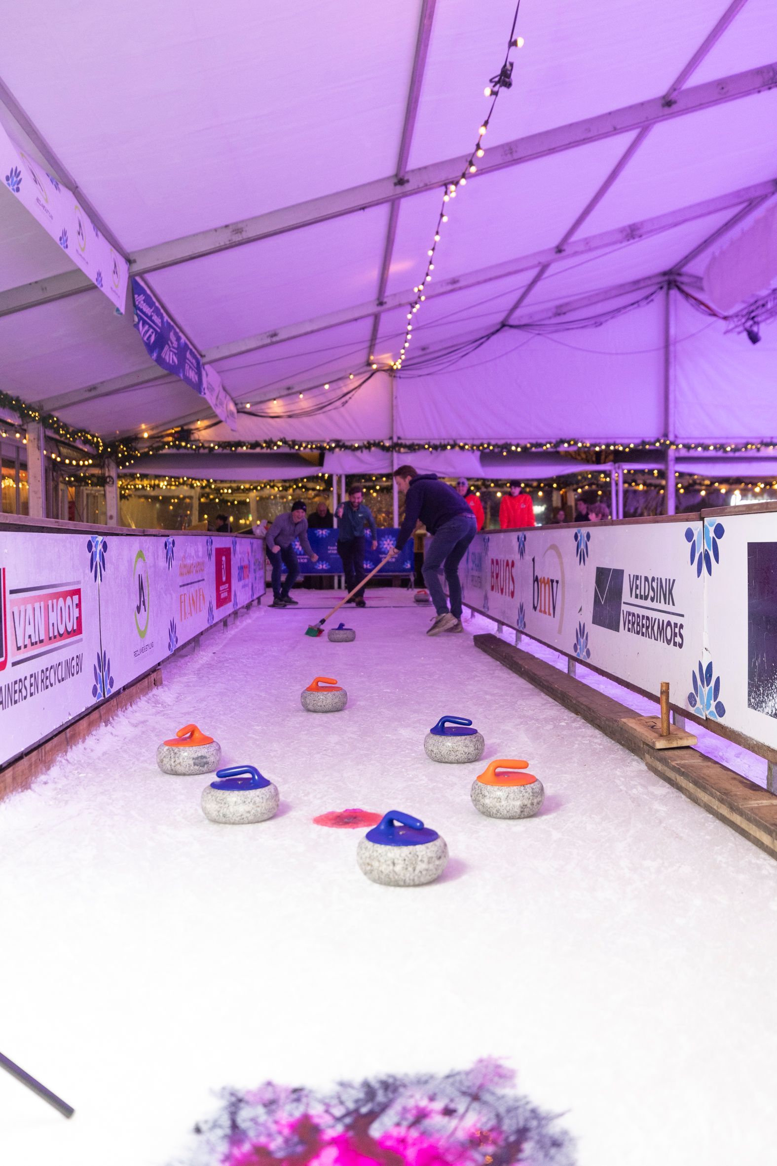Een groep mensen speelt curling op een ijsbaan.