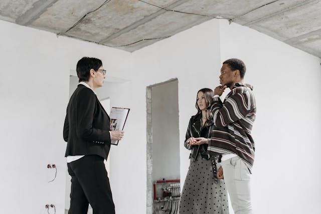 woman-with-clipboard-talking-to-two-people-in-renovated-space