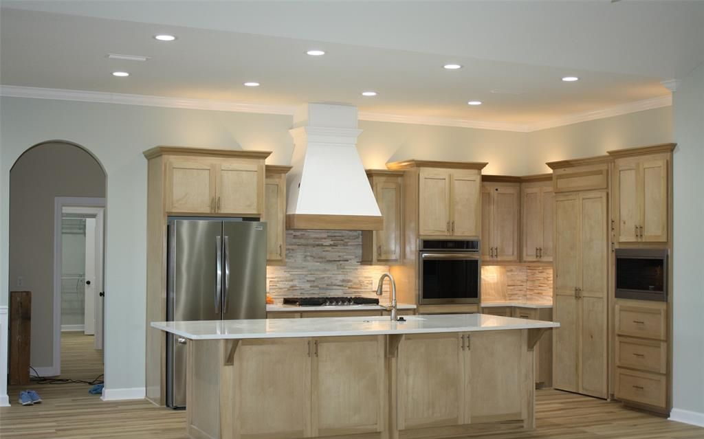 Kitchen with light wood cabinets, stainless steel appliances, and a large island.