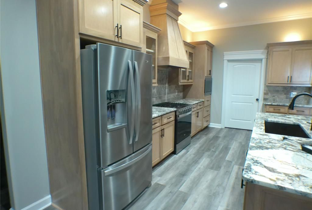 Kitchen with stainless steel refrigerator, light-colored cabinets, and gray flooring.