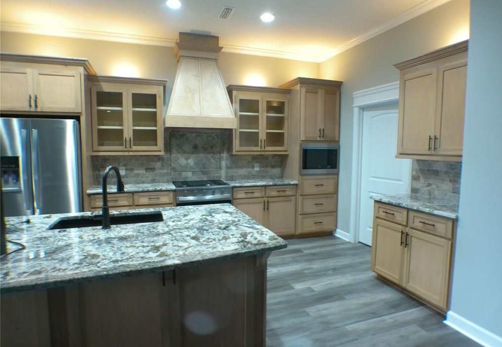 Kitchen with island, light wood cabinets, stainless steel appliances, and granite countertops.
