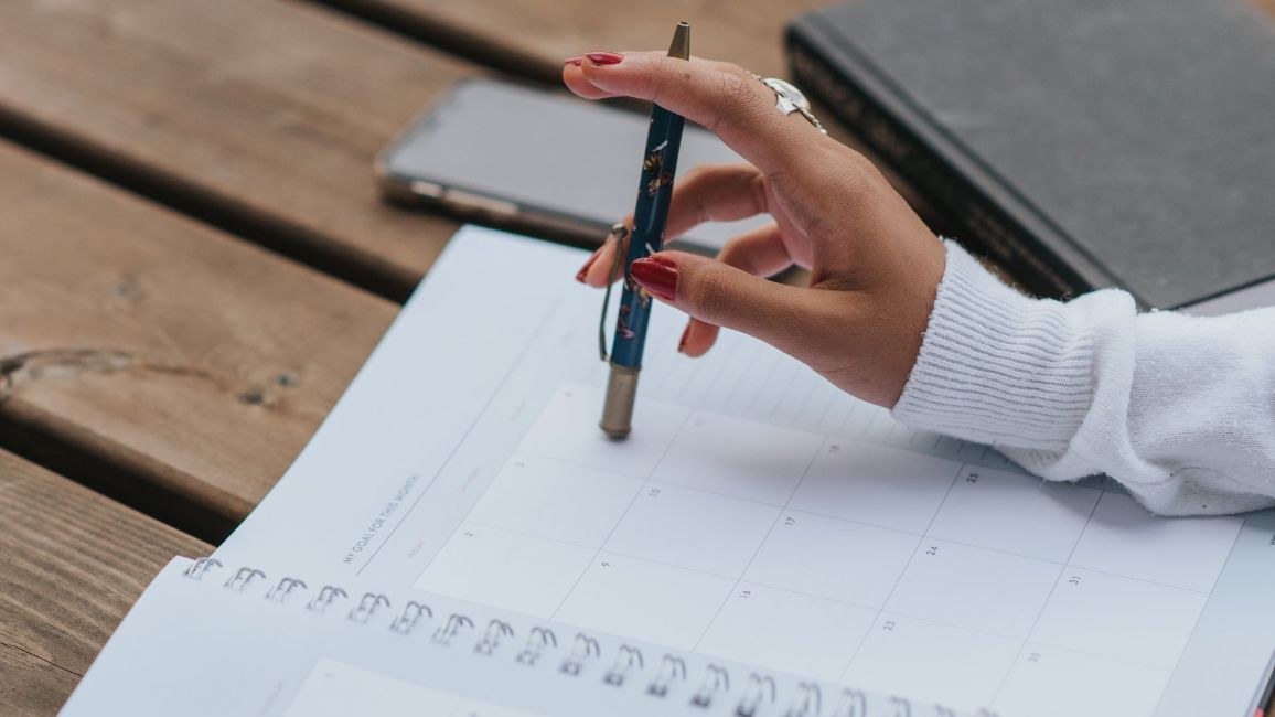 A woman is writing in a notebook with a pen.