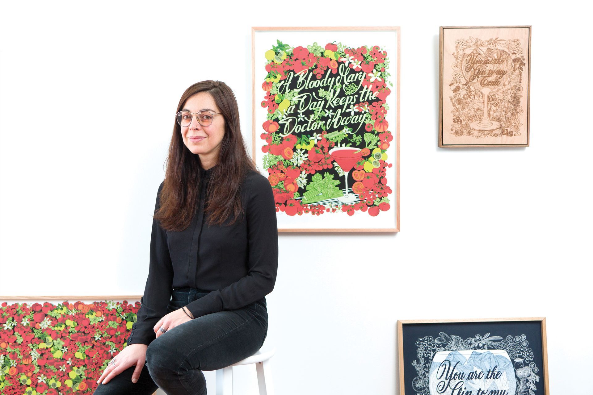 Maria Montes portrait in front of four of her illustrated cocktail artworks for her first solo show 'Breaking the ice'.