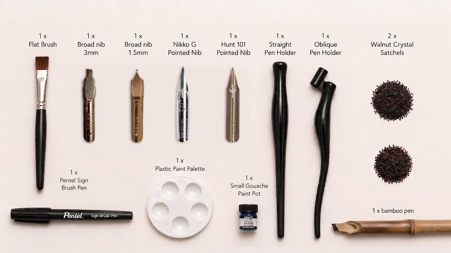 Calligraphy kit laid out with pens, nibs, ink, palette, and paper examples on a white background