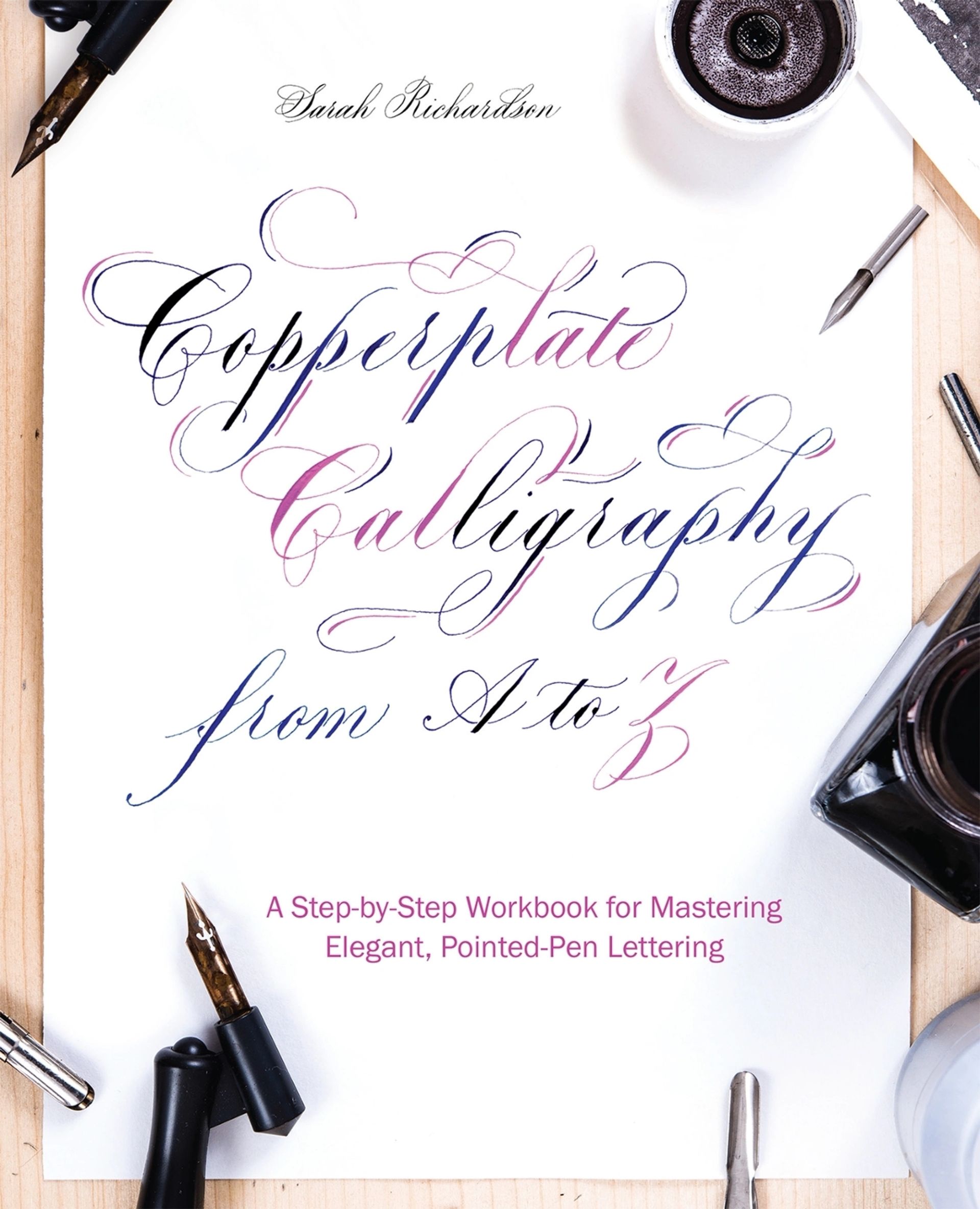 Copperplate calligraphy book cover with elegant script, pens, ink, and white desk background